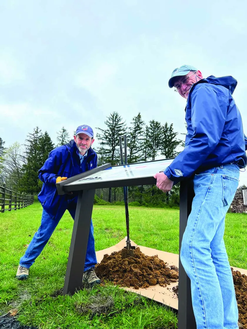 Two men help install a new sign at Lee’s Headquarters.