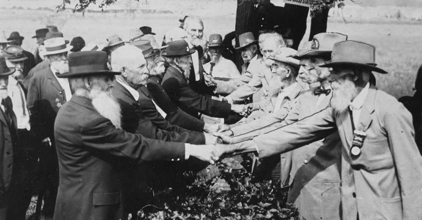 A black and white photo of Union and Confederate veterans shaking hands