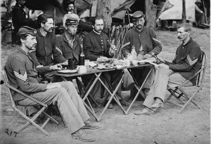 A photograph of soldiers eating at a table.