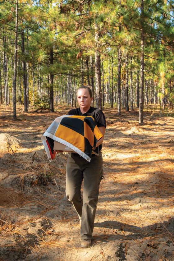 SCIAA Archaeologist and veteran Sara Rogers carries the remains of a Maryland Continental from the field.