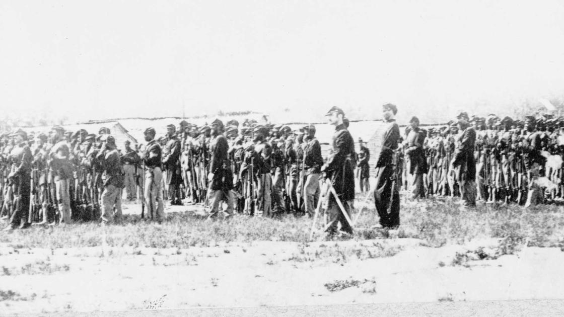 Photograph shows troops in formation during review.