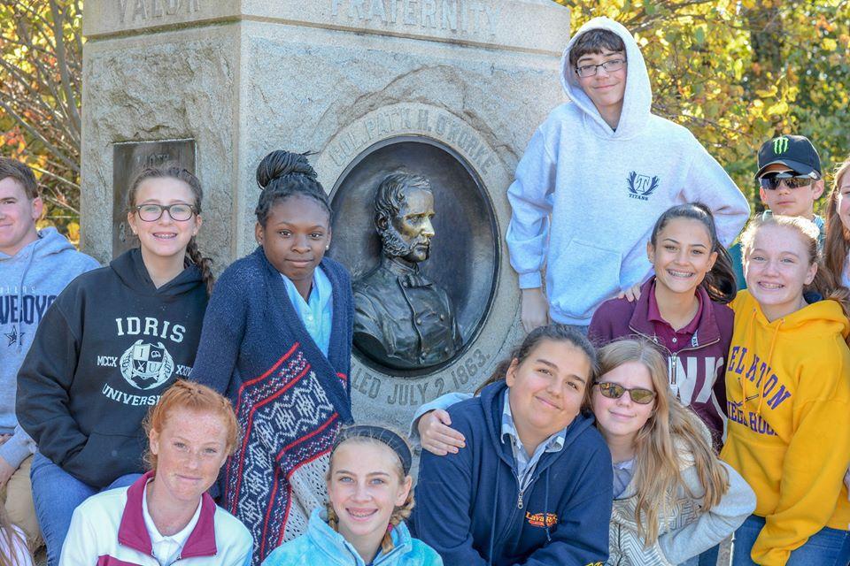 Students post with their teacher in front of a marker at Gettysburg.