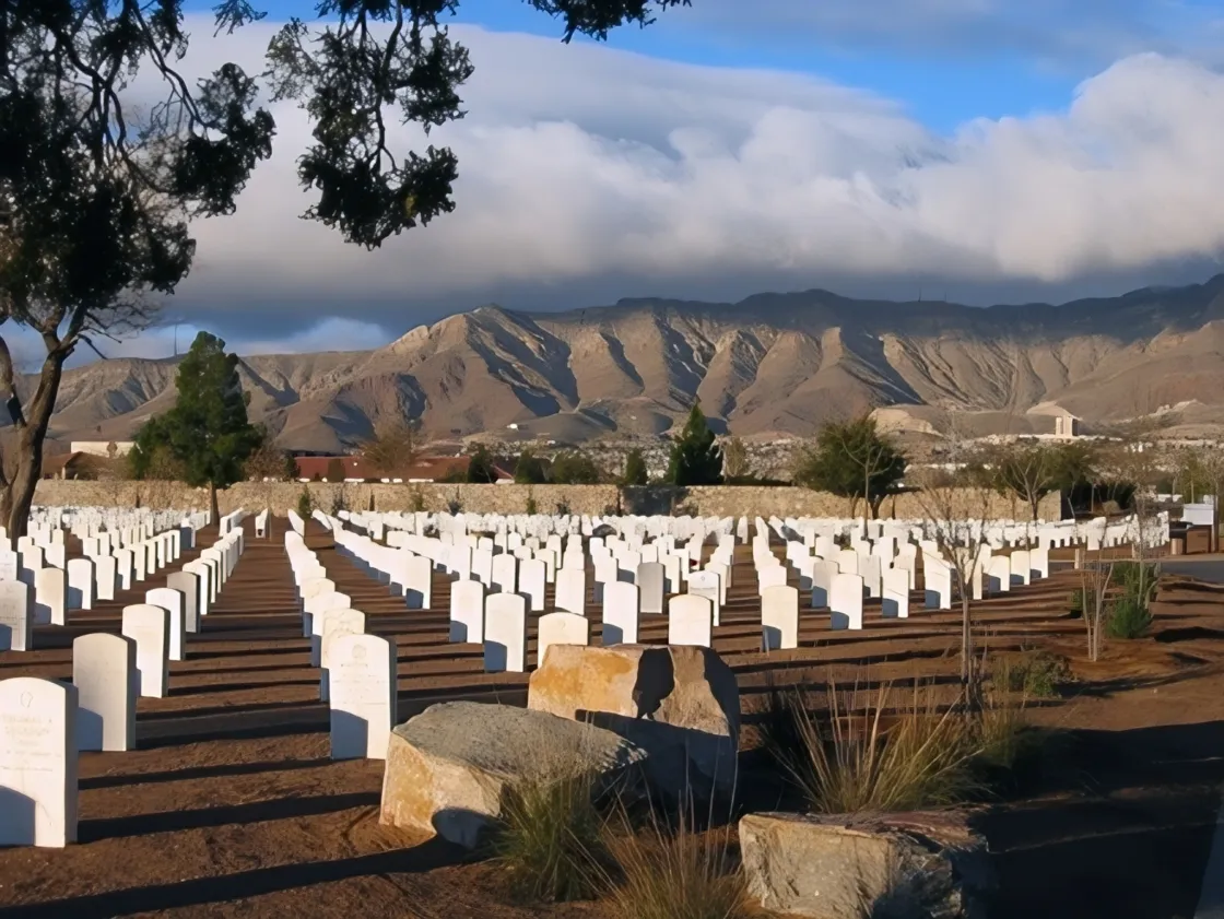 Rows of white tombstones with Franklin Mountain range in background.