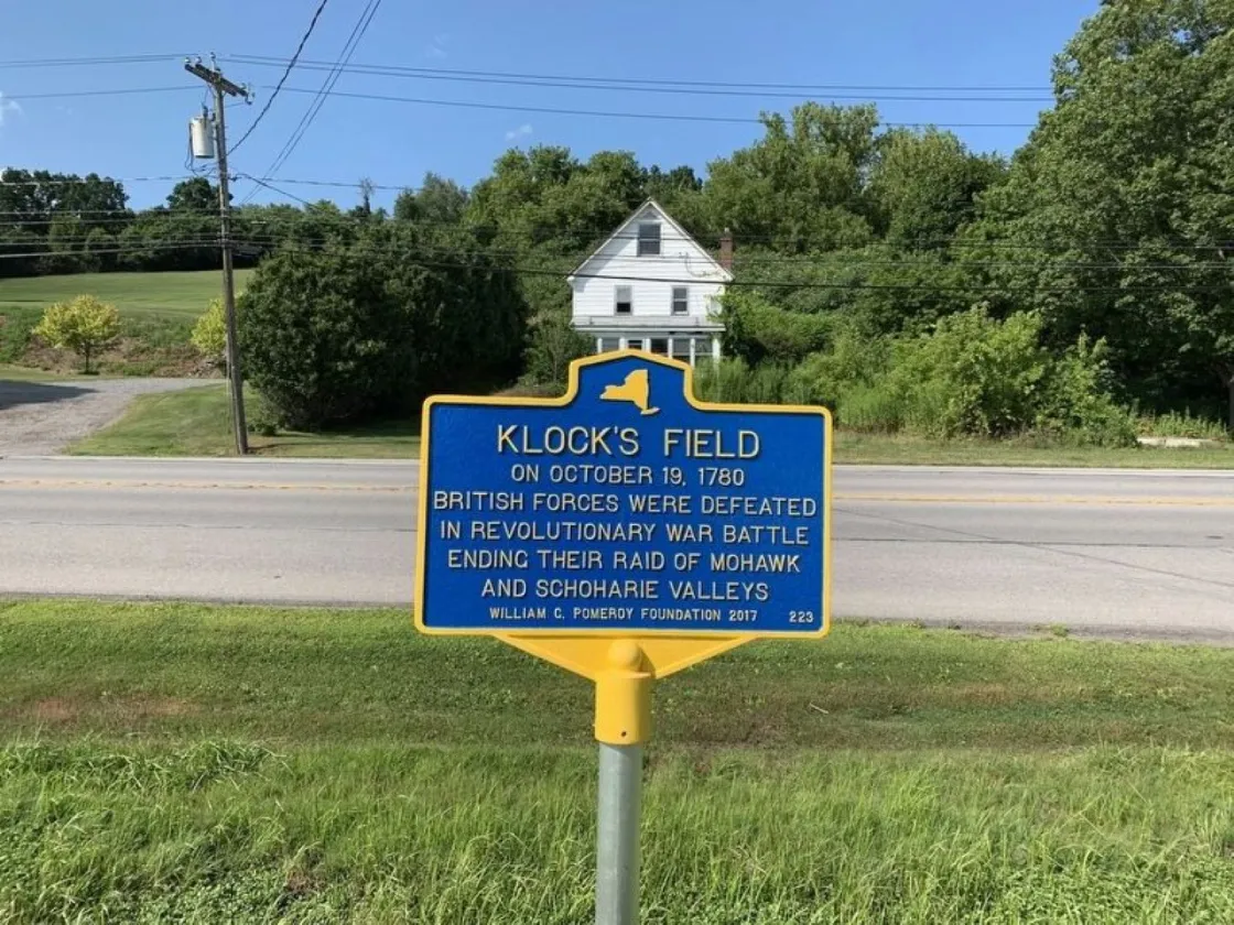 Site of Battle of Klock's Field Marker denoted by blue and yellow metal plaque.