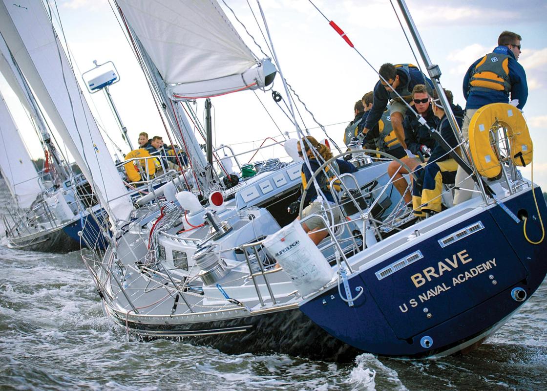 Close-in shot of a sailing vessel named "Brave - U.S. Naval Academy" leaning while under sail