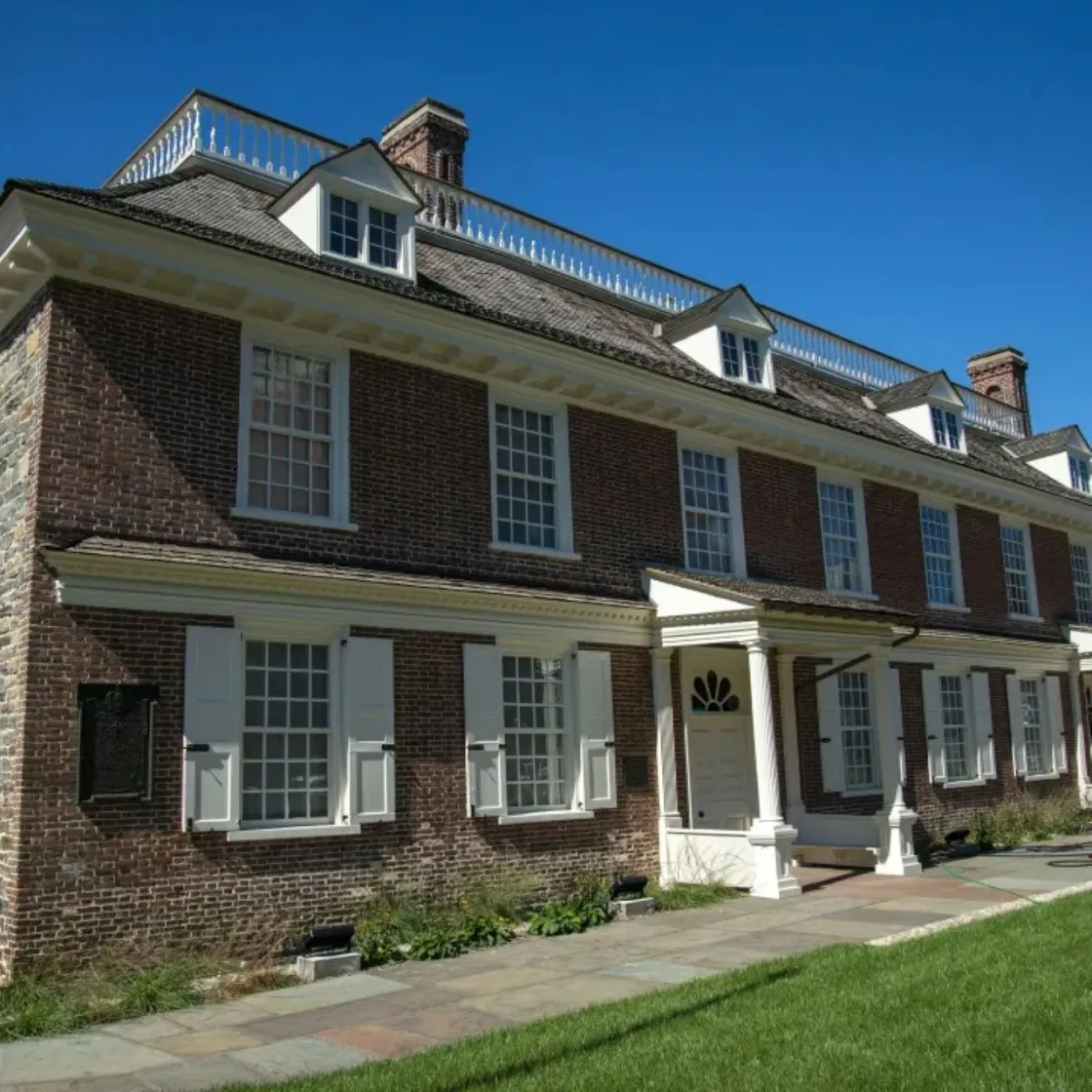 Colonial era 2-story red brick manor house with 11 windows and 3 dormer windows trimmed in white.