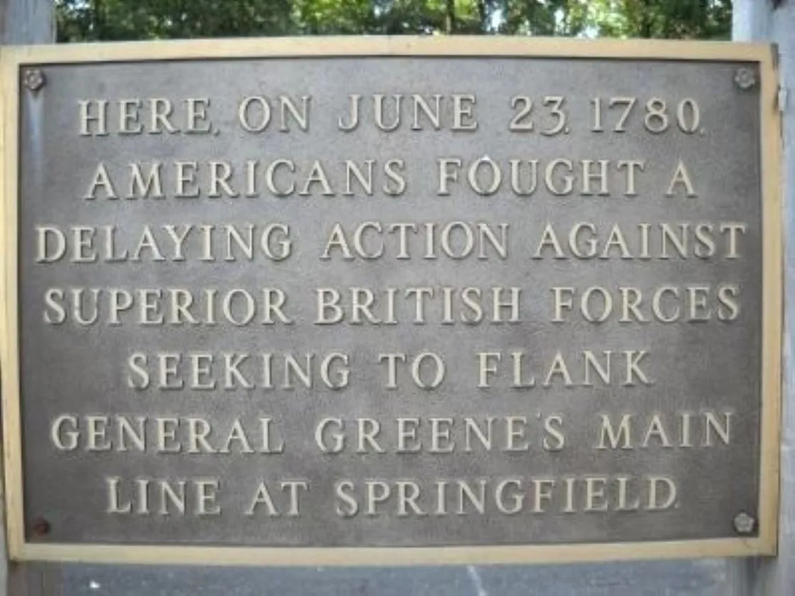 A bronze plaque mounted on a stone surface commemorates a June 23, 1780 battle where Americans delayed advancing British forces near Springfield.