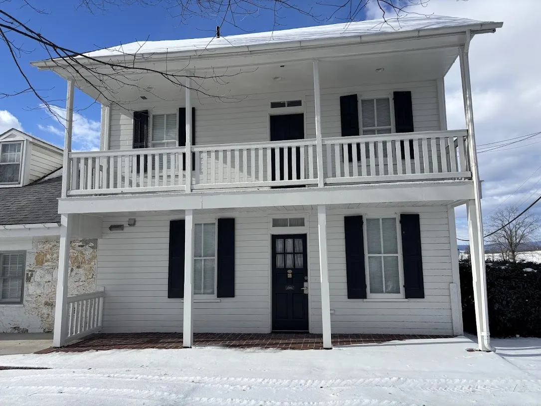 The front exterior of a historic house, painted white.