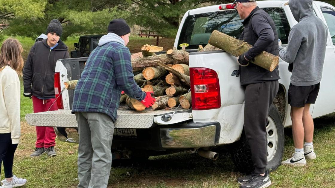 Volunteers unload wood from a white pickup truck