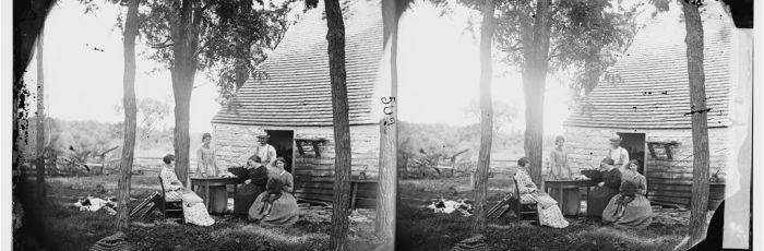 Photograph of a family sitting in front of a home near Cedar Mountain