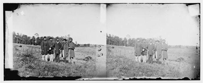 Photograph of of five men from the 10th Maine Regiment standing amidst horse carcasses after the Battle of Cedar Mountain