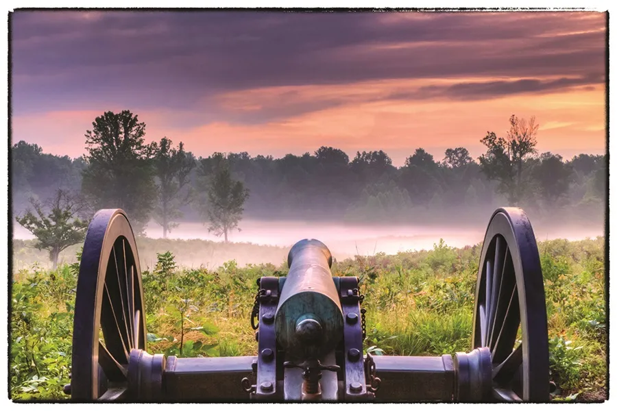 This is an up-close photograph of a cannon with an incredible sunset in the background.