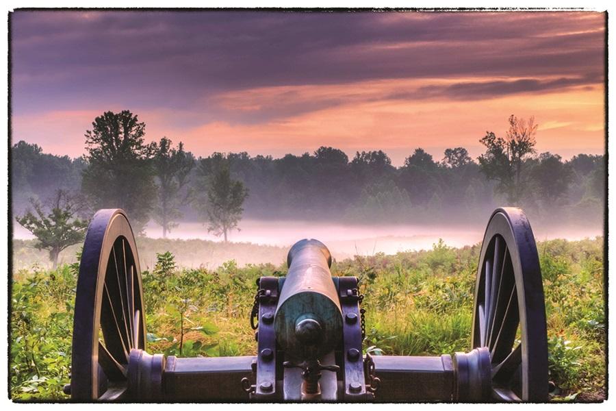 This is an up-close photograph of a cannon with an incredible sunset in the background.